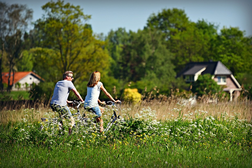 Man and Woman Riding Bicyles in Field of Flowers Man and Woman Riding Bicyles in Field of Flowers