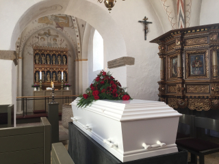 Casket in a Church White With Red Flowers on Top