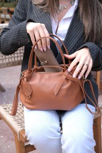 woman reaching into her handbag pulling out smaller pouch