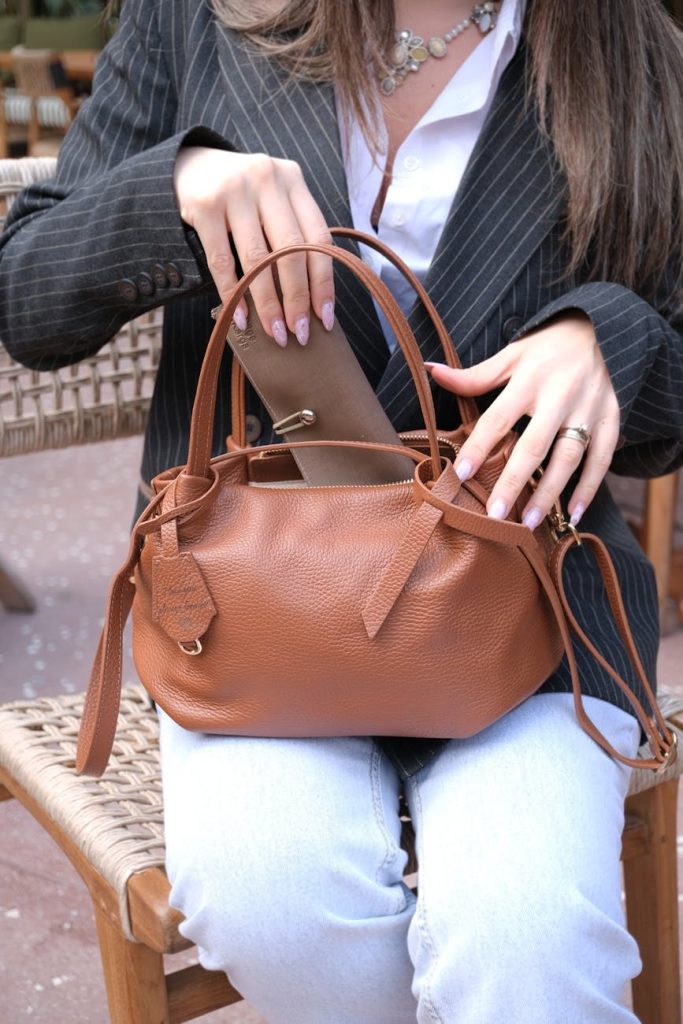 woman reaching into her handbag pulling out smaller pouch