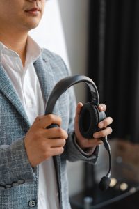 man in gray plaid jacket holding black headphones