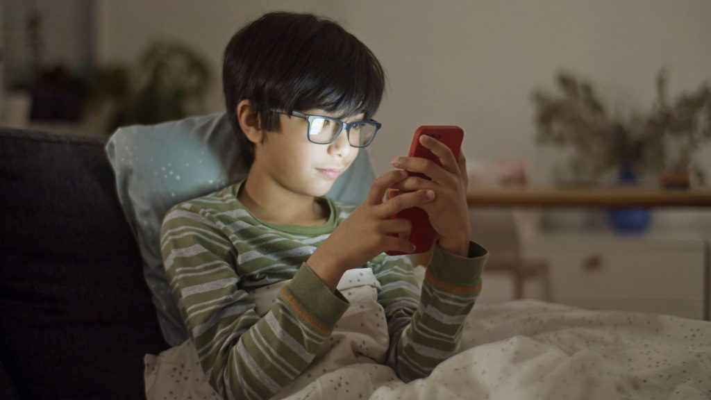 boy in striped long sleeves using a smartphone