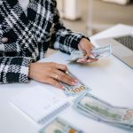 OppFi seeks to make payday loans in every state by acquiring a national bank, coalition warns person sitting on the table counting money