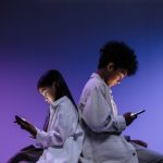 kids sitting back to back using smartphones