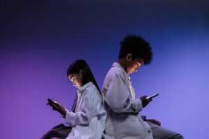kids sitting back to back using smartphones