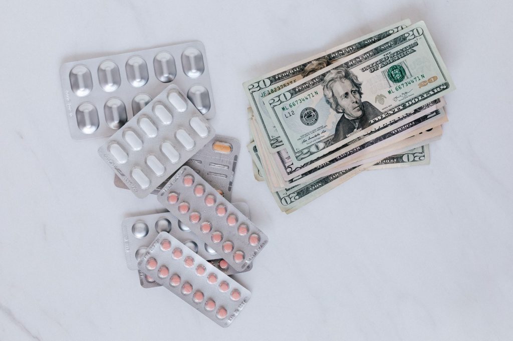 set of pills with heap of paper money