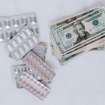 set of pills with heap of paper money
