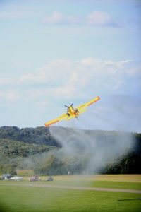 yellow crop duster spraying field in scenic landscape